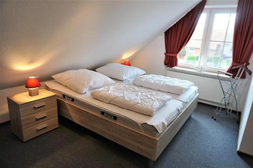 a bed in a room with a large window at Robbeninsel in Norden