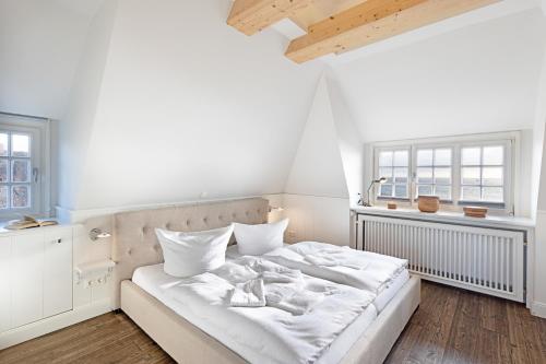 uma cama branca num quarto com duas janelas em Syltbeach em List