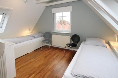 Schlafzimmer im Dachgeschoss mit 2 Betten und 2 Stühlen in der Unterkunft Olhörnweg 2 in Wyk auf Föhr