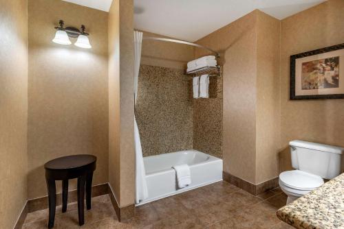 y baño con bañera, aseo y taburete. en Lloyd Hotel Astoria Bayfront, Ascend Hotel Collection, en Astoria, Oregon