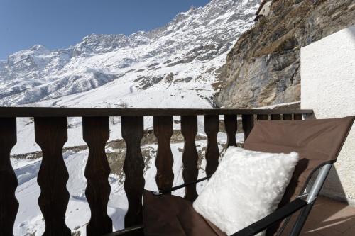 a chair on a balcony with a snow covered mountain at HelloChalet - Pandora Mountain View with jacuzzi, garage and ski storage in Breuil-Cervinia