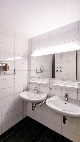 two sinks in a bathroom with white tiled walls at Ferienwohnung Eichhorn in Schwangau