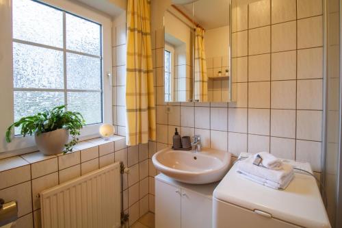 ein weißes Badezimmer mit einem Waschbecken und einem Spiegel in der Unterkunft Teewulkje in Greetsiel
