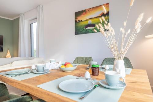 una mesa de comedor con platos blancos y tazas. en Villa 17 Appartement Blickwinkel, Lohme, en Lohme