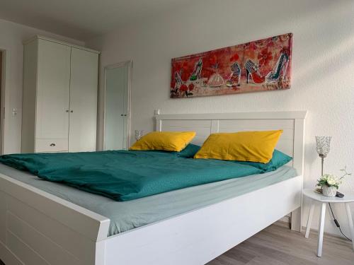 a large bed with green sheets and yellow pillows at Ferienwohnung Nordseebrandung A2.5 in Sahlenburg