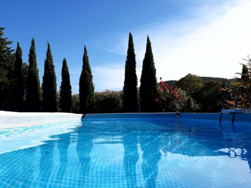 ein blauer Pool mit Bäumen im Hintergrund in der Unterkunft Maison indépendante sur notre propriété in Hyères