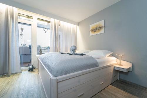 ein weißes Schlafzimmer mit einem Bett und einem Fenster in der Unterkunft Berolina Wohnung 315 in Dahme
