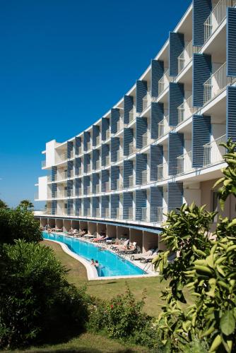 a large apartment building with a swimming pool and chairs at TUI Blue Barut Andız - All Inclusive - Adults Only in Side