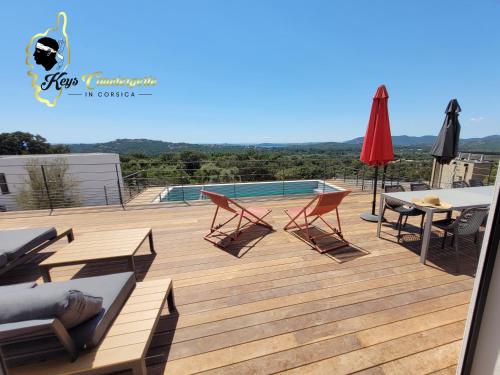 eine Terrasse mit Stühlen, einem Tisch und einem Sonnenschirm in der Unterkunft Casa Balancinu Vue panoramique sur montagne et Mer Piscine Privée in Sainte-Lucie de Porto-Vecchio