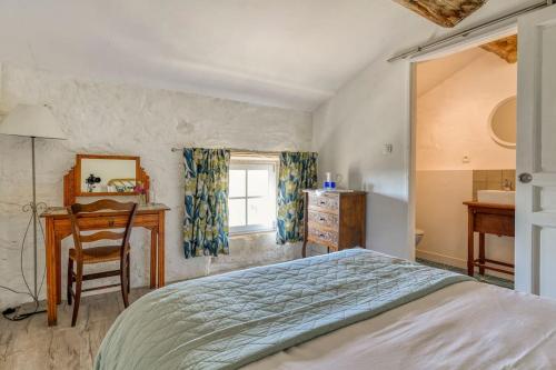 a bedroom with a bed and a desk and a window at La Calade in Montouliers