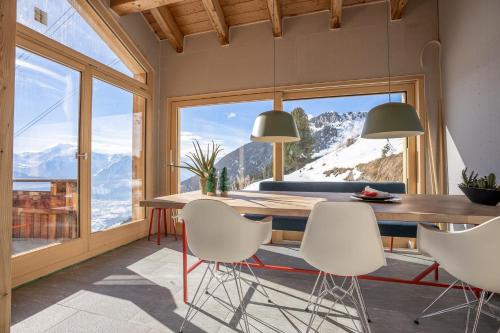 a dining room with a table and views of mountains at Chalet Elsa in Riederalp