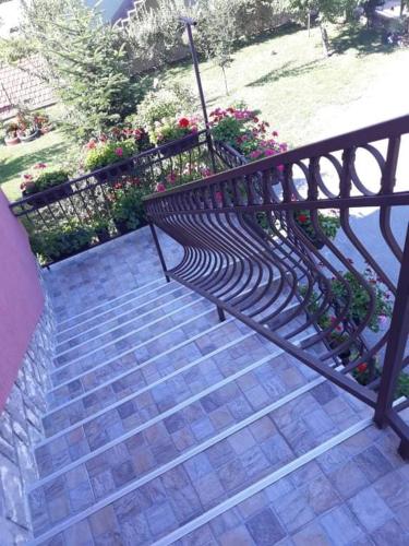 a black bench sitting on a set of stairs with flowers at Apartman Drina in Berilovac