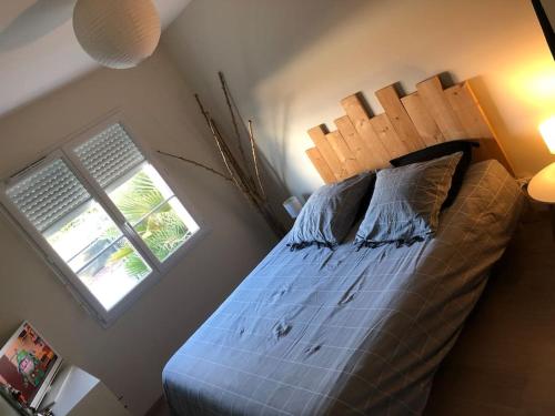een slaapkamer met een bed met een houten hoofdeinde en een raam bij Maison avec piscine privative in Biganos
