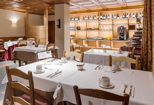 a restaurant with white tables and chairs and a kitchen at Hotel Chalet Bassibe by Silken in Baqueira-Beret