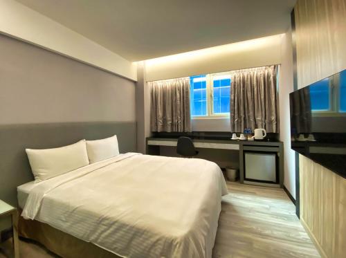 1 dormitorio con cama, escritorio y ventana en Hub Hotel Ximen Inn, en Taipéi