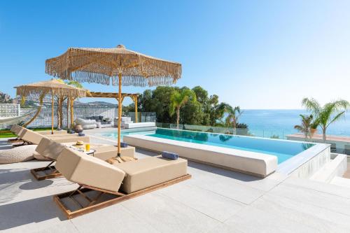 a villa with a swimming pool with chairs and an umbrella at Lido Blue Villa in Pefki Rhodes