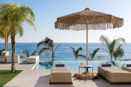 a resort with a swimming pool with chairs and an umbrella at Lido Blue Villa in Pefki Rhodes