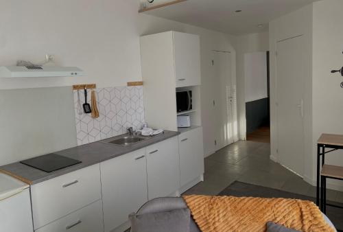 une cuisine avec des armoires blanches et un évier dans l'établissement Le quai des marins, à Châteauroux