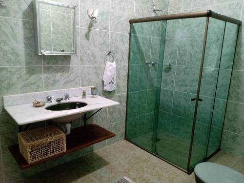 uma casa de banho com uma cabina de duche em vidro e um lavatório. em Pousada Canto da Paz em Petrópolis
