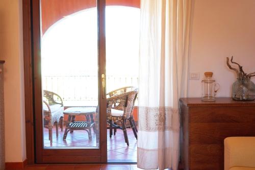 Zimmer mit einer Tür, die auf einen Balkon mit einem Tisch führt. in der Unterkunft Mereu Central Apartment in Villasimius