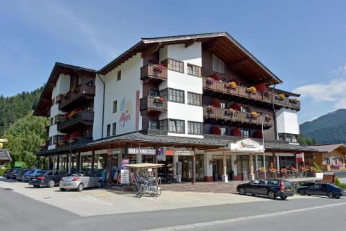 un grande edificio con auto parcheggiate in un parcheggio di Das Alpin - Hotel Garni Guesthouse a Scheffau am Wilden Kaiser
