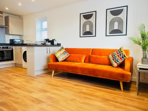 um sofá laranja numa sala de estar com uma cozinha em Private Parking Stylish Great Location em Guildford