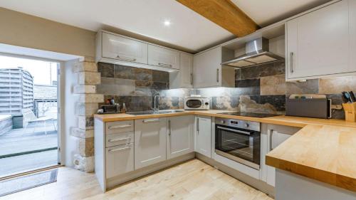 a kitchen with white cabinets and a large window at Church View Apartment in Stow on the Wold