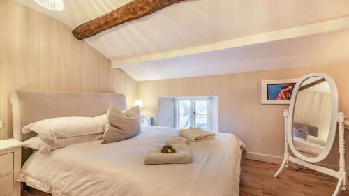 a bedroom with a large white bed with a mirror at Church View Apartment in Stow on the Wold