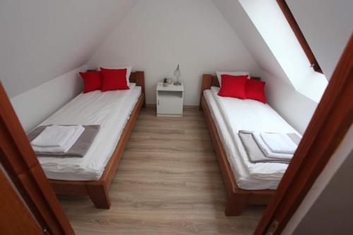 2 camas en una habitación pequeña con almohadas rojas en Panorámás Vendégház, en Vértestolna