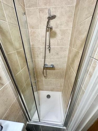 um chuveiro com uma porta de vidro na casa de banho em SE4, Self contained studio flat. em Londres