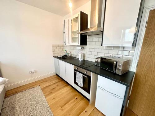 a kitchen with a black counter top and a microwave at SE4, Self contained studio flat. in London