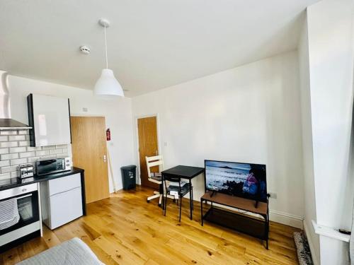 a living room with a kitchen with a table and a television at SE4, Self contained studio flat. in London
