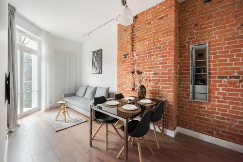 a living room with a brick wall and a table and chairs at East Warsaw Modern Apartment in Warsaw