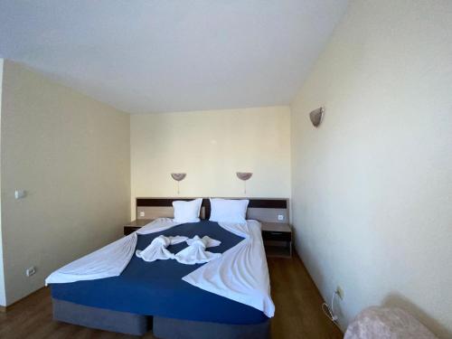 ein Schlafzimmer mit einem blauen Bett mit weißer Bettwäsche in der Unterkunft VECHNA R 18 Studio Sunny Beach in Sonnenstrand