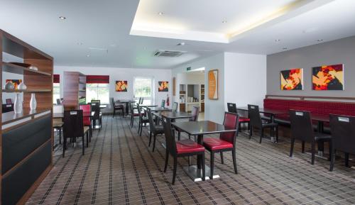 a dining room with tables and chairs in a restaurant at Holiday Inn Express Warwick - Stratford-upon-Avon, an IHG Hotel in Warwick