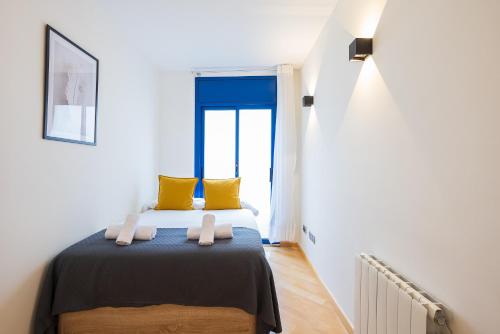 a bedroom with a bed with yellow pillows and a window at Lucas House Apartments by Sitges Group in Sitges