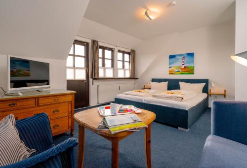 ヴェニングシュテットにあるHaus Düneneckのベッド、テーブル、ソファが備わるホテルルームです。
