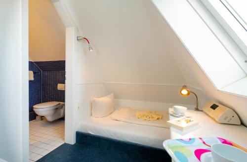 ヴェニングシュテットにあるHaus Düneneckのベッドとトイレ付きの小さな屋根裏部屋です。
