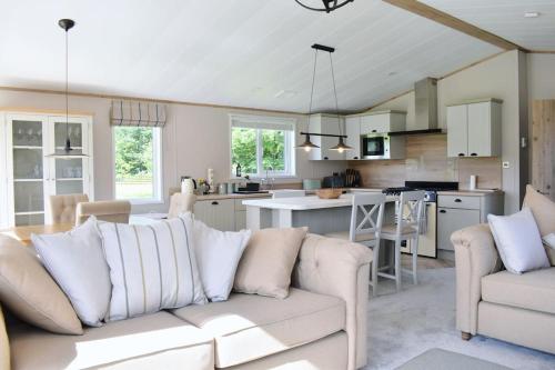 a living room with a white couch and a kitchen at Snittlegarth Farm Lodges in Wigton