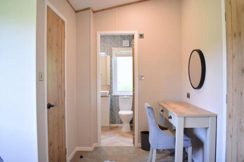 a bathroom with a desk and a toilet and a mirror at Snittlegarth Farm Lodges in Wigton