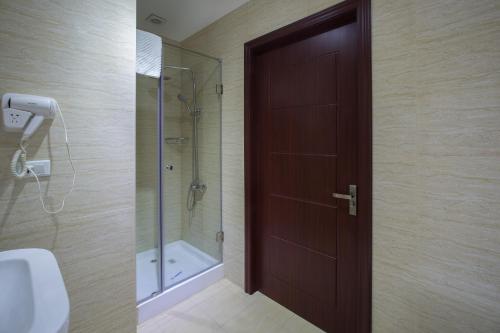La salle de bains est pourvue d'une douche et d'une porte en bois. dans l'établissement Diamond Hotel Yerevan, à Erevan