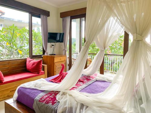 a bedroom with a bed with a mosquito net at Merthayasa Bungalow 2 in Ubud