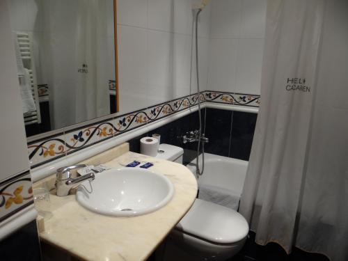 a bathroom with a sink and a toilet and a mirror at Hotel Casa Carmen in Benabarre
