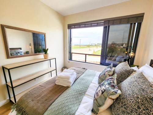une chambre avec un lit et une grande fenêtre dans l'établissement Kabeljauws Beach Apartments, à Jeffreys Bay