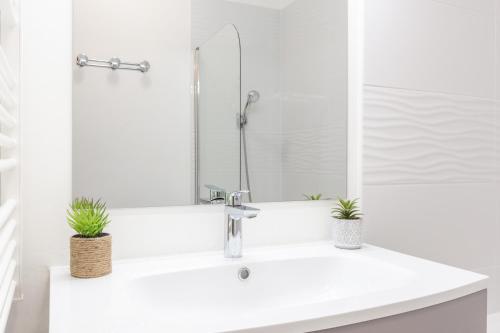 a white bathroom with a sink with two plants on it at La Bohème in Montévrain