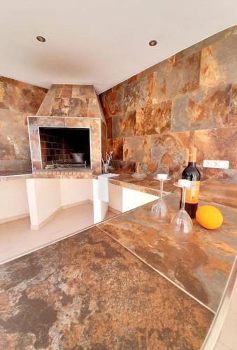 a room with a stone fireplace and a counter with wine bottles at Casa El Rafal in Porreres