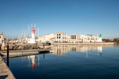 un grand volume d'eau avec un phare et des bâtiments dans l'établissement La Casa Tranquilia chez Véro et JJ Studio à Marseillan, à Marseillan