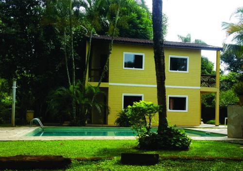 una casa amarilla con una piscina frente a ella en Vila da Praia en Boicucanga