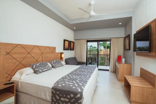 a bedroom with a large bed and a television at Riu Santa Fe - All Inclusive in Cabo San Lucas