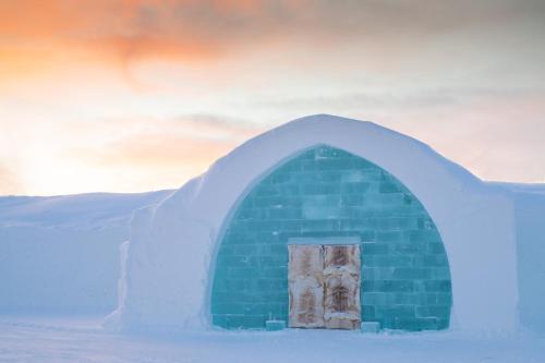 un petit igloo avec une porte dans la neige dans l'établissement Icehotel, à Jukkasjärvi